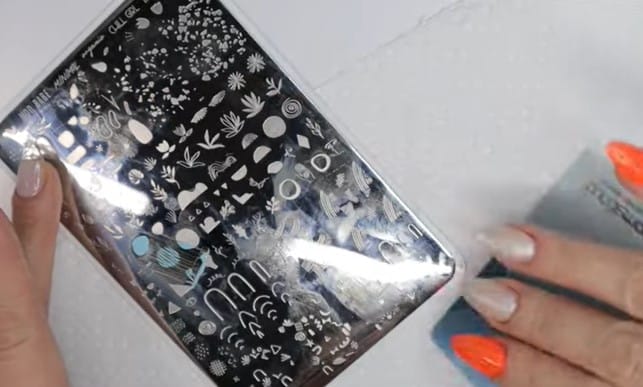 Stamping Nail Polish: Step 2, select an engraving, paint polish and use the scraper to remove the excess
